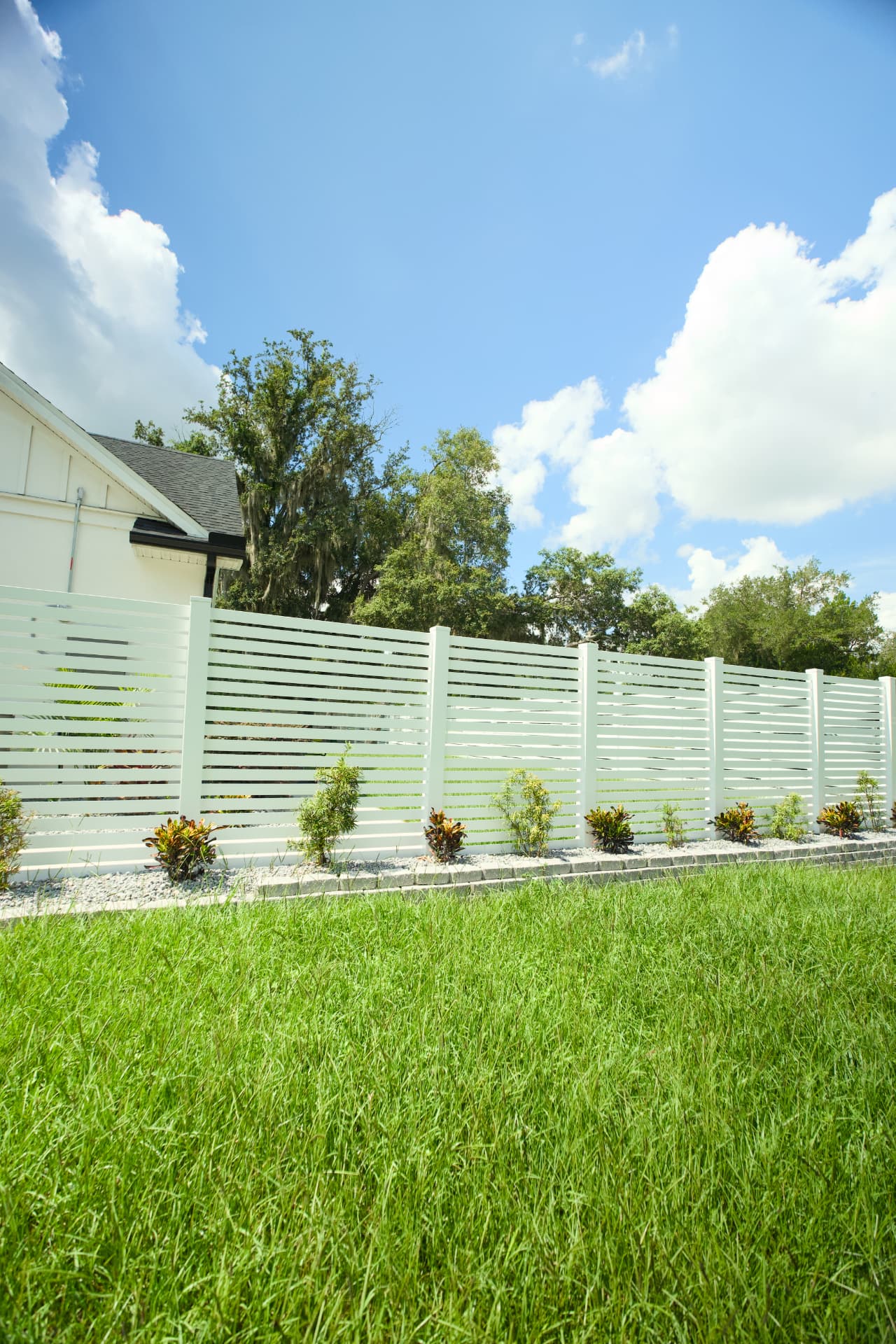 White vinyl privacy fence with horizontal slats in a Florida backyard