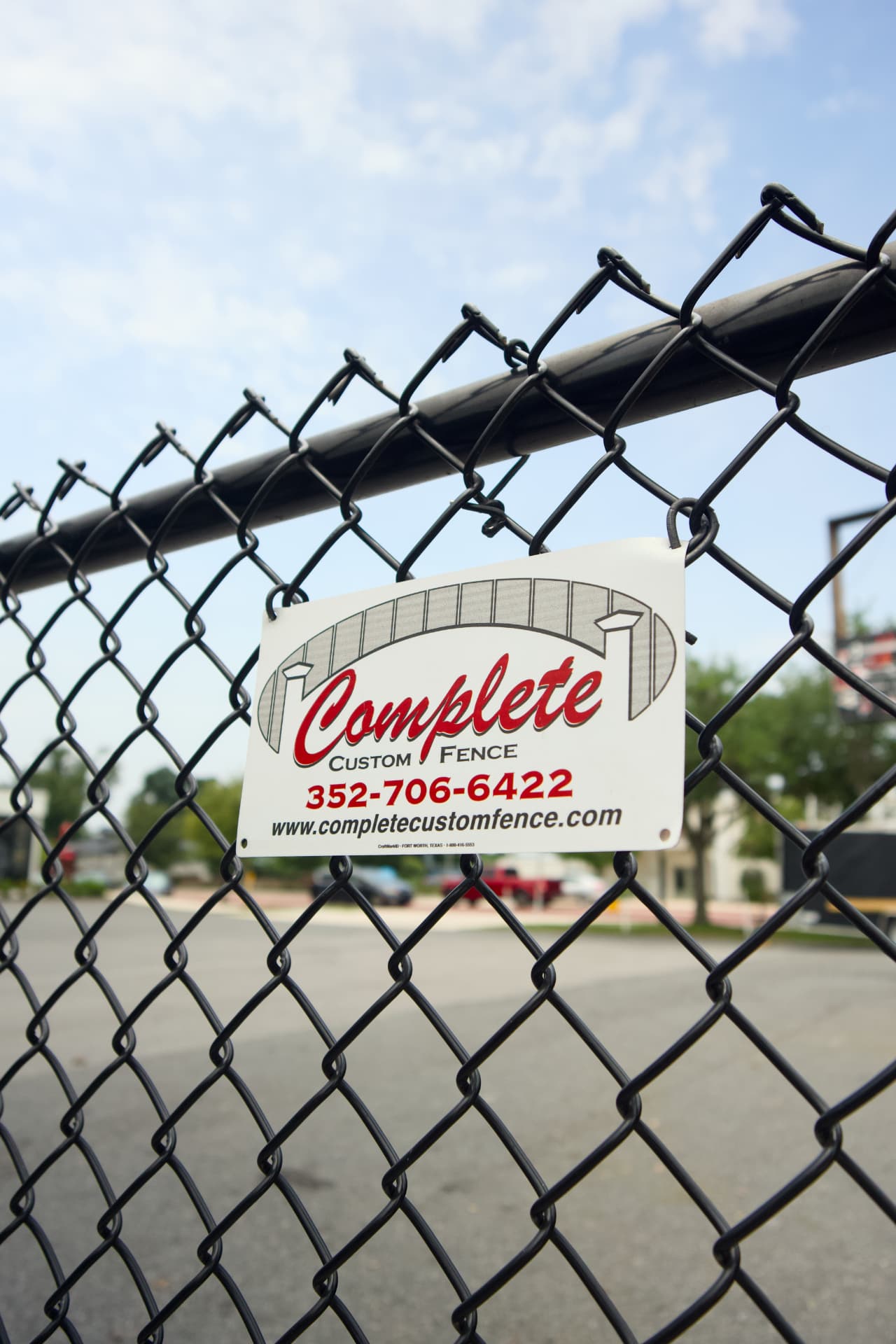 Black chain link fence with a Complete Custom Fence sign